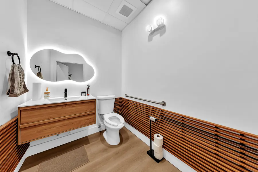 Restroom with a backlit cloud-shaped mirror and wood slat wall