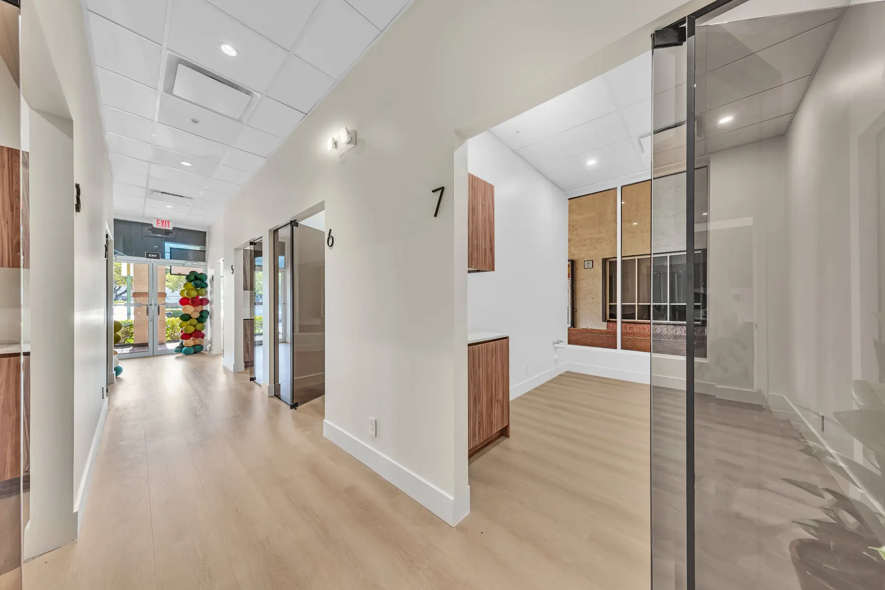 Hallway with numbered suites and glass doors leading to the entrance
