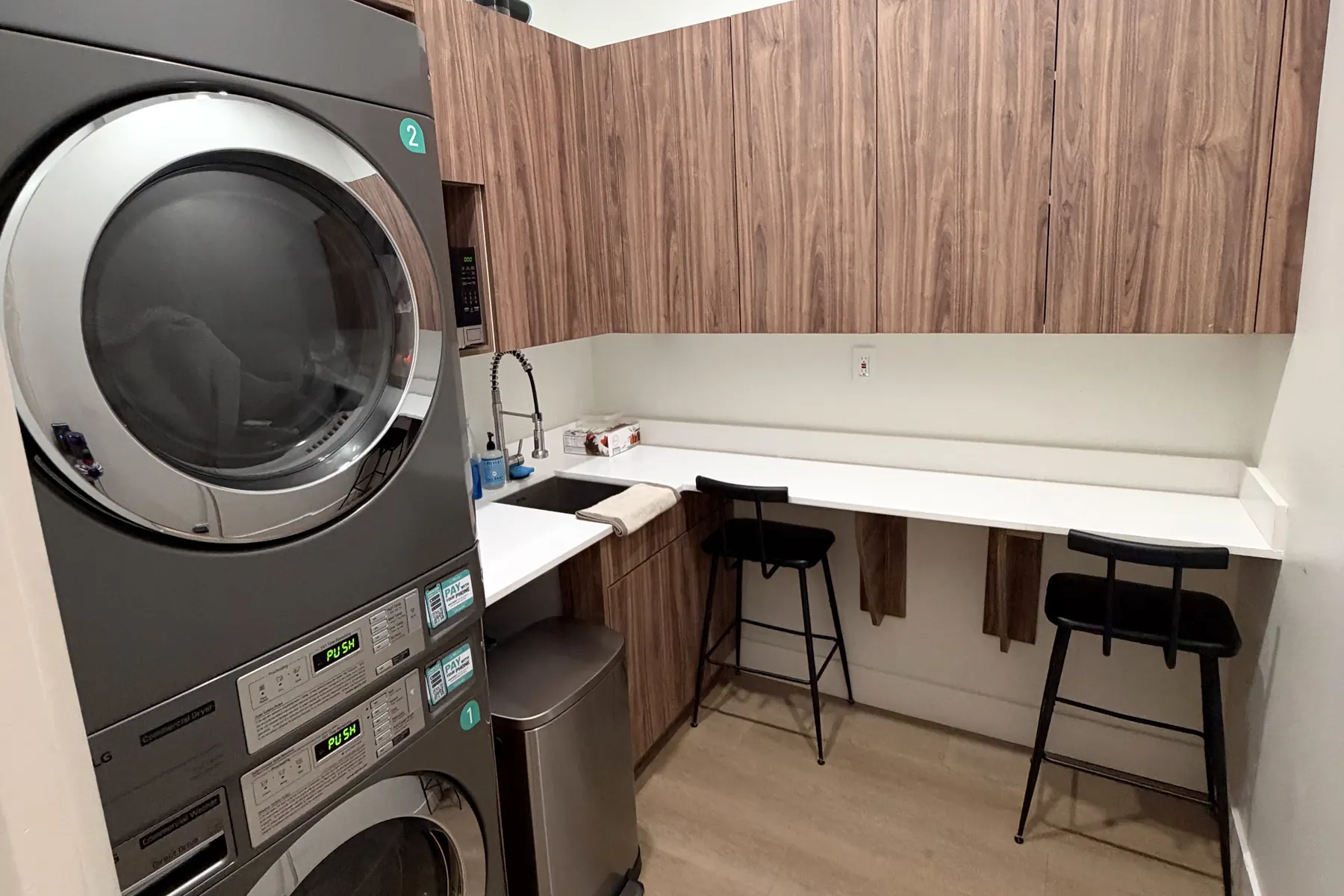 Laundry room with stacked washers and dryers, walnut cabinets, a counter and bar stools